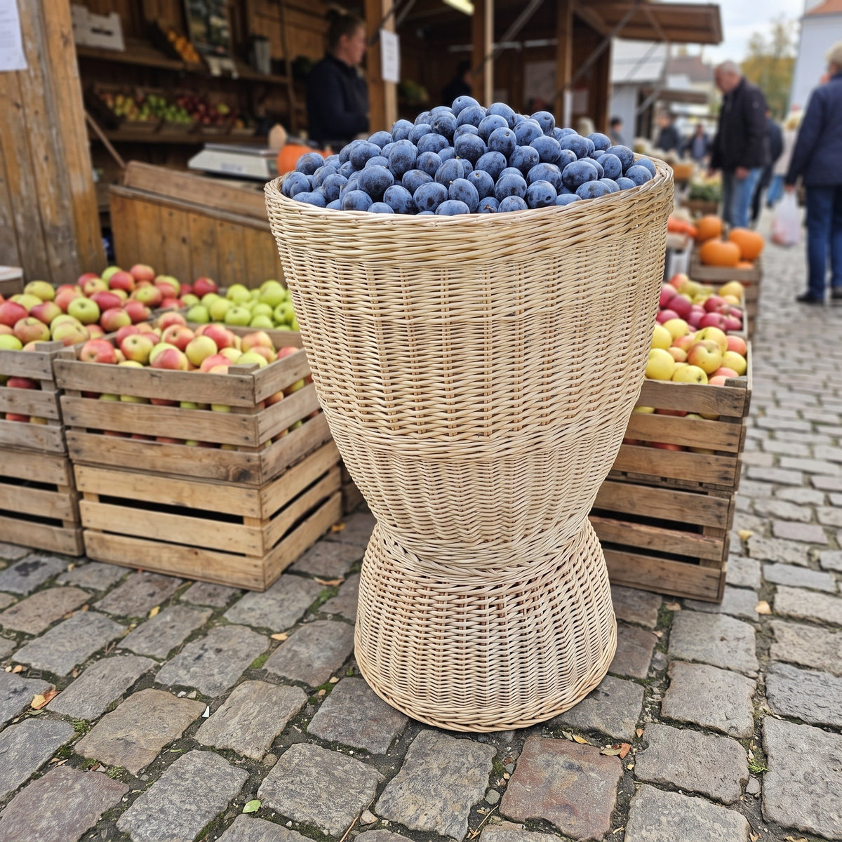 Aukšta pintinė, pilna slyvų, lauko turguje ant grindinio prie dėžių su obuoliais