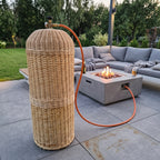 Pintas gaubtas prie betoninio ugnies stalo modernioje terasoje, šalia lauko sofa, žarna eina į degiklį