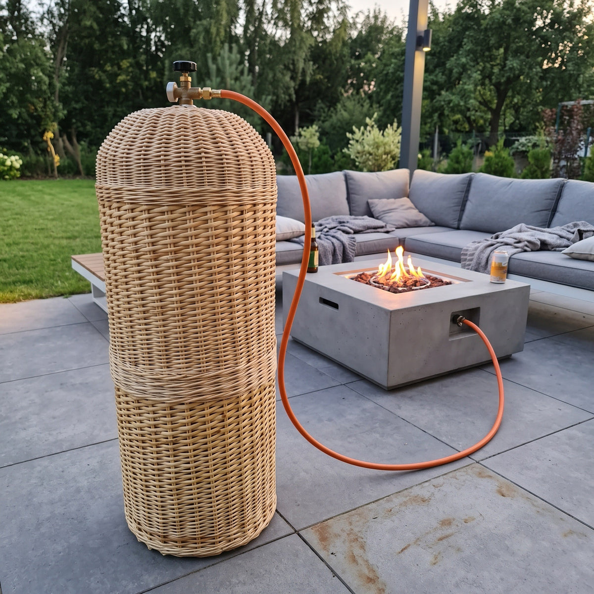 Pintas gaubtas prie betoninio ugnies stalo modernioje terasoje, šalia lauko sofa, žarna eina į degiklį