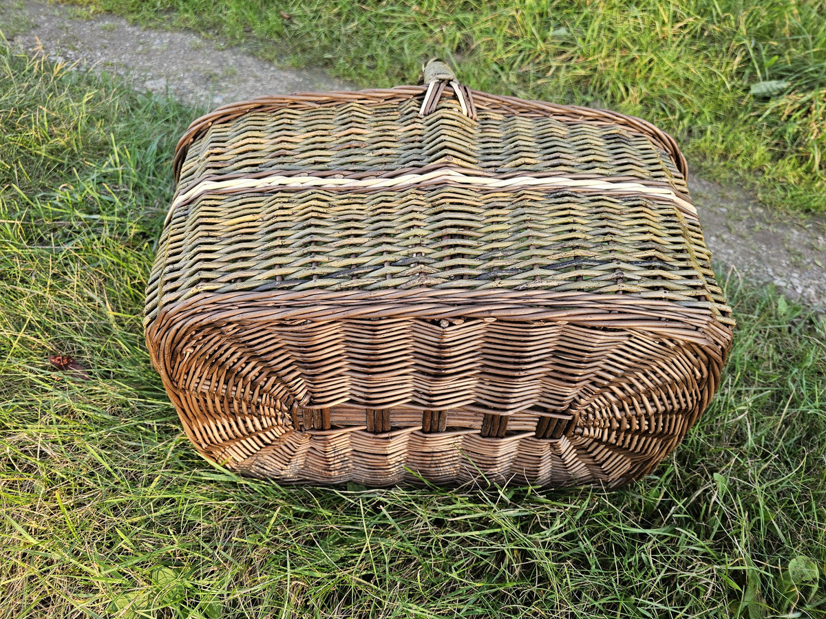 The large rectangular wicker basket turned upside down on the grass, showing the sturdy woven base