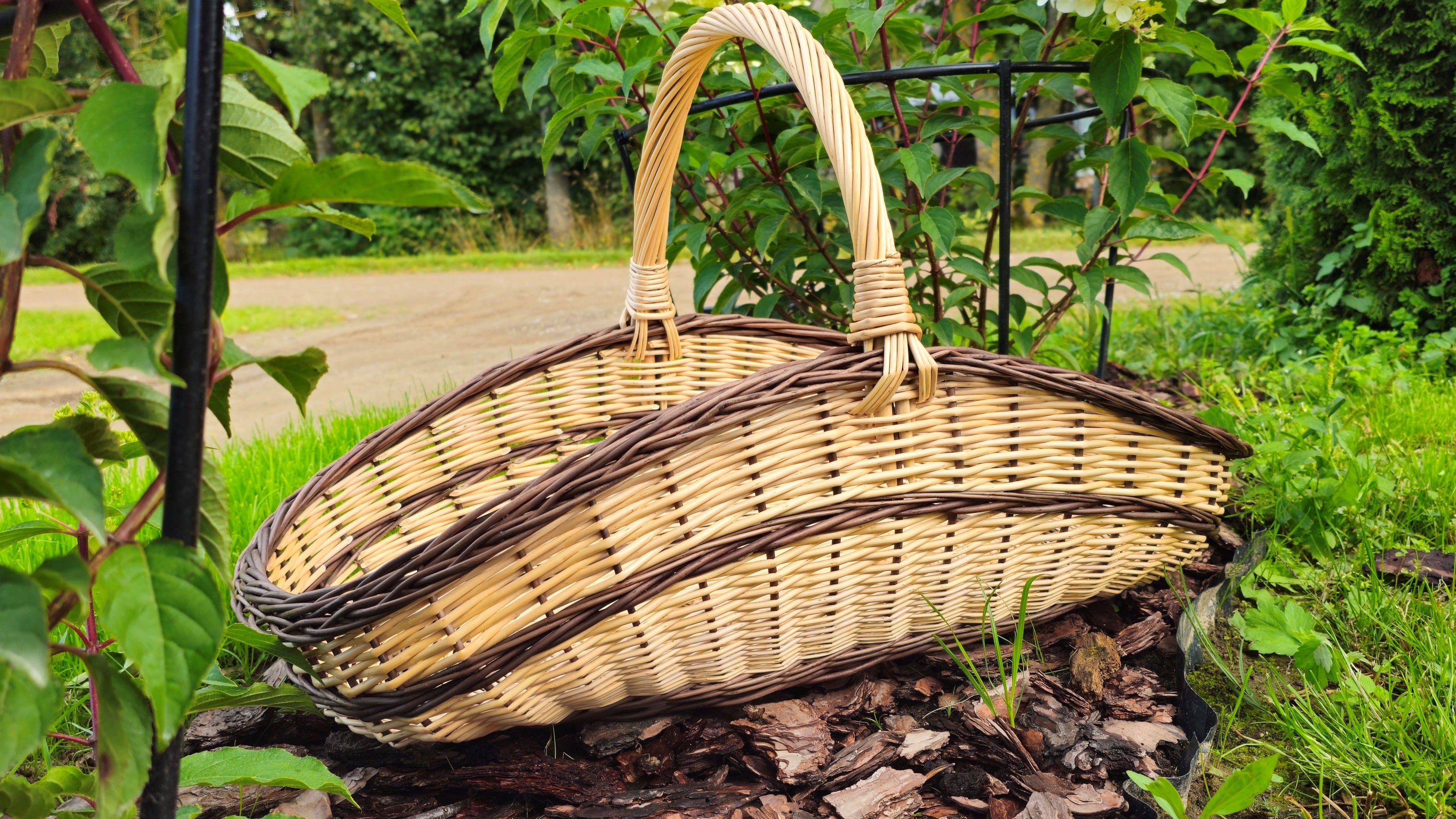 Wicker basket on a tree trunk with greenery and flowers in the background