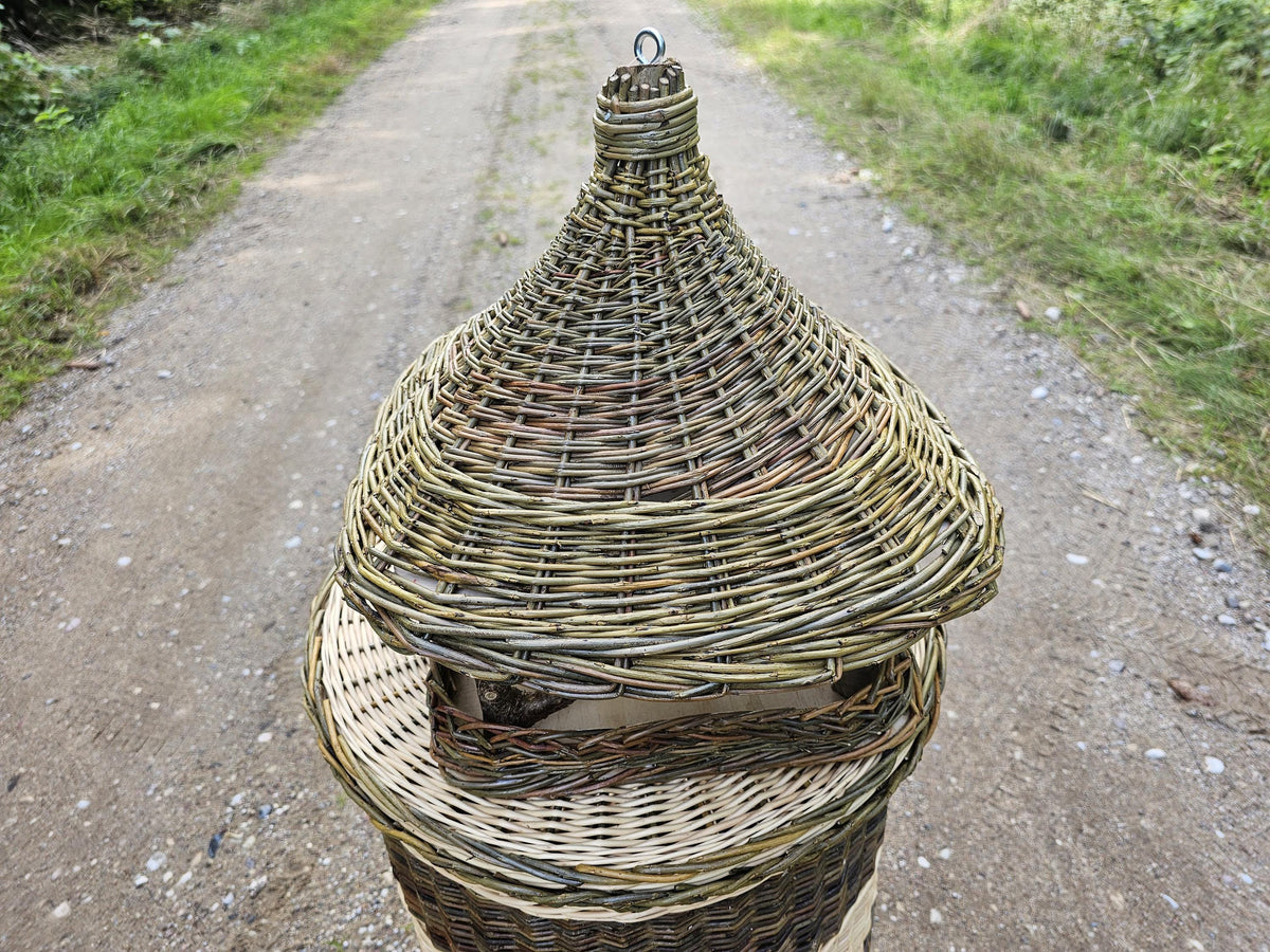 Lesykla iš arti ir iš priekio ant kaimo keliuko, pintas kūgio formos stogelis užima visą kadrą