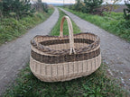 Large oval willow basket on a gravel path between fields