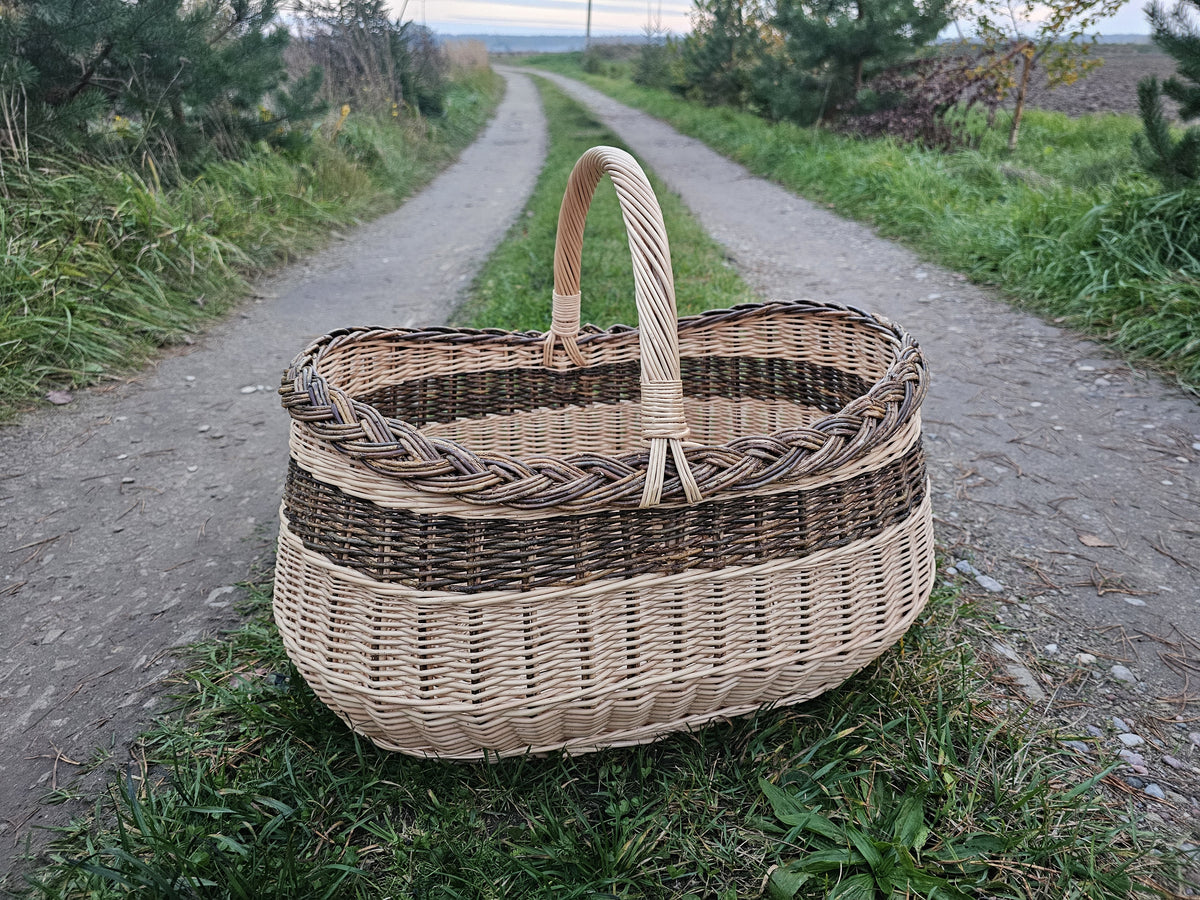 Large oval willow basket on a gravel path between fields