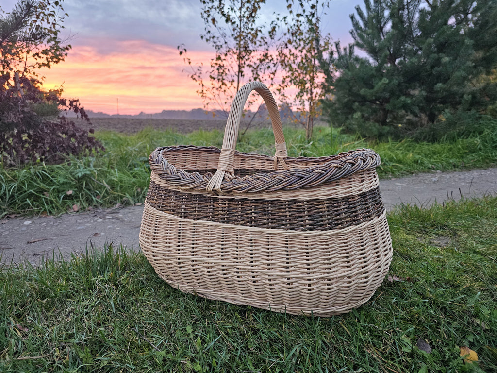 Large oval willow basket in a field with an evening sky behind it