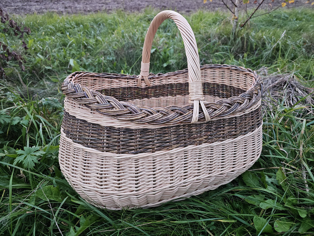 Large oval willow basket with tall handle in long grass