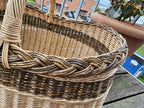 Large oval willow basket seen from above at an angle, showing the braided rim and the inside