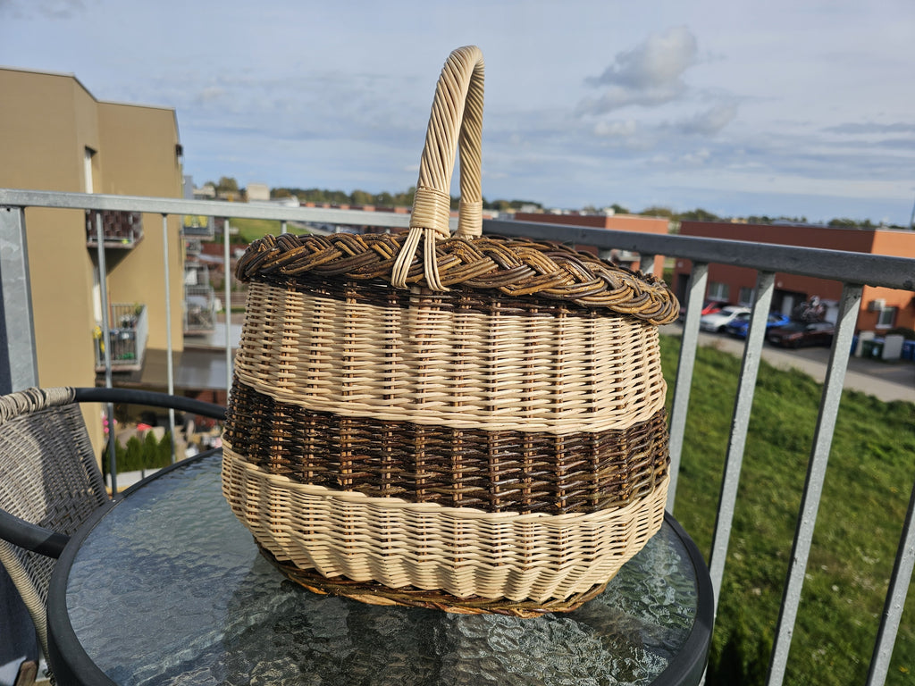 Turgaus pintinė su kasele pintu kraštu ir susukta rankena ant stiklinio sodo staliuko saulėtame balkone