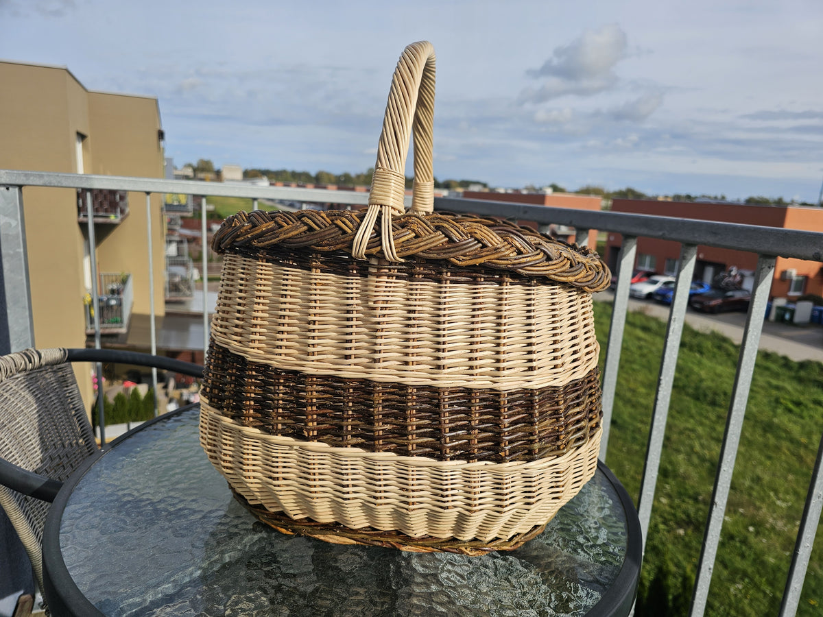 Turgaus pintinė su kasele pintu kraštu ir susukta rankena ant stiklinio sodo staliuko saulėtame balkone