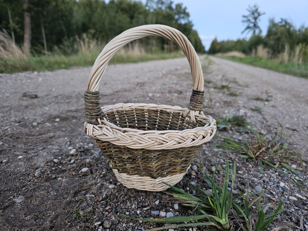 Maža apvali pintinė gėlių mergaitei su kasele pintu kraštu ir uogomis, ant šiaudų tarp braškių