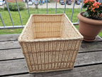 Didelė stačiakampė pintinė, 45 × 35 × 32 cm, iš luptų vytelių su storu kasele pintu kraštu ir iškiliomis juostomis ant medinio balkono stalo